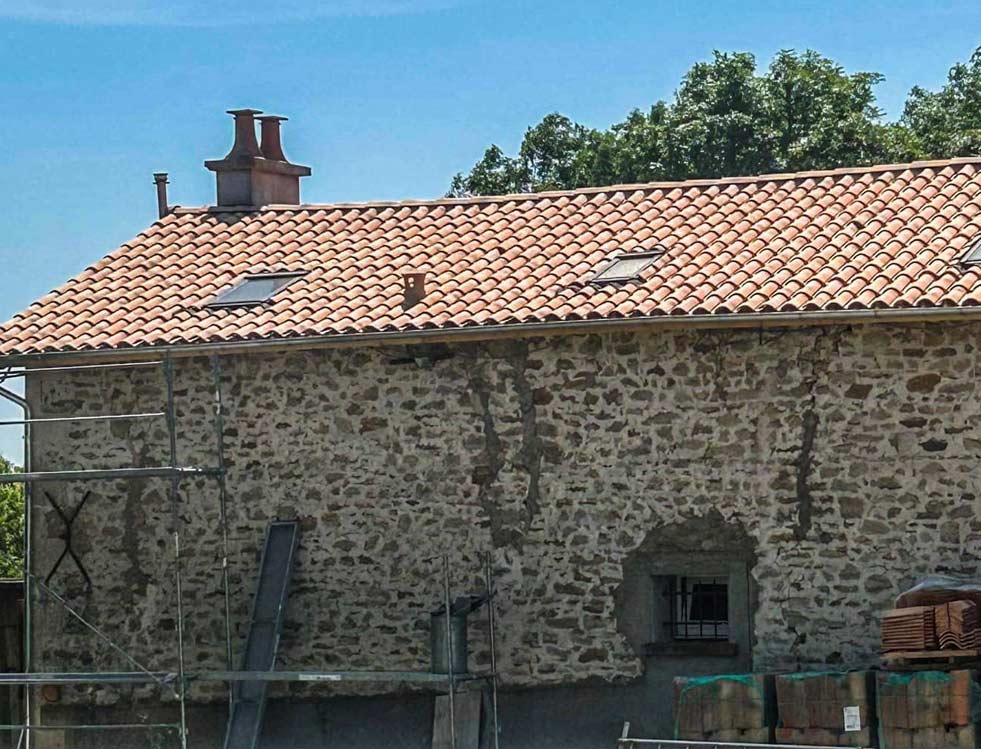 Une maison en pierre avec un toit en tuiles et une cheminée
